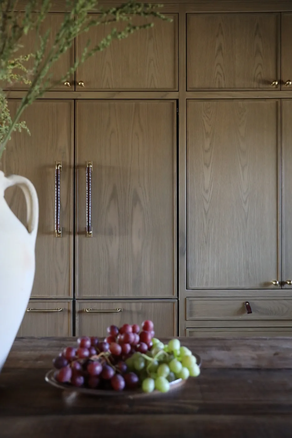Tall wood cabinetry with long vertical brass pulls