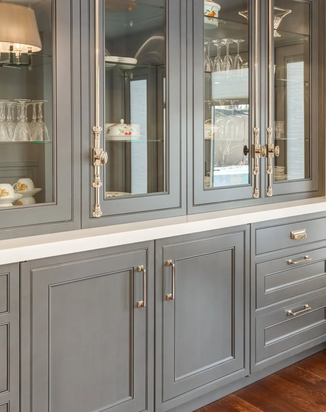 Grey cabinetry with mixed brass hardware and glass-front uppers
